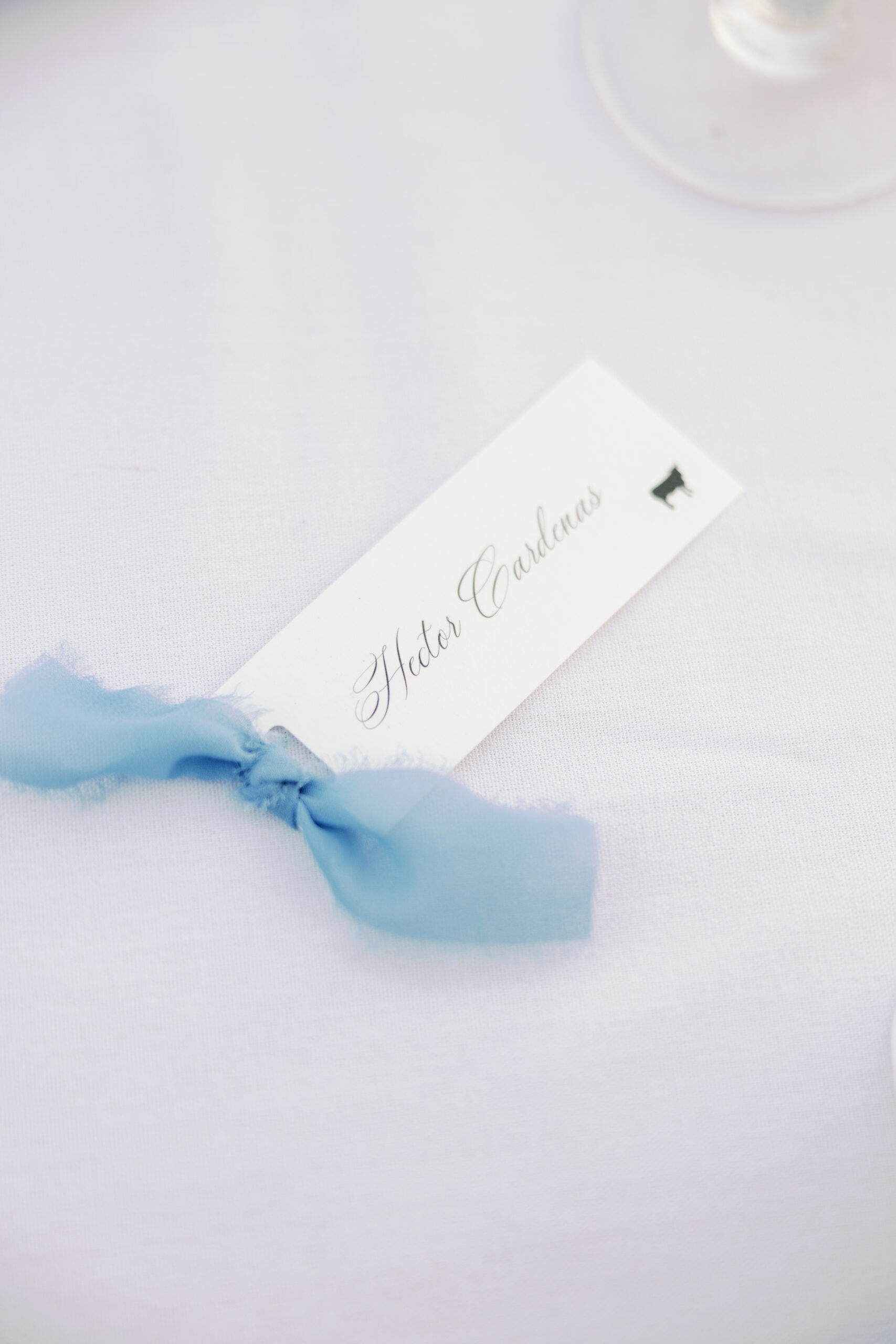 dusty blue ribbon place card on a white tablecloth